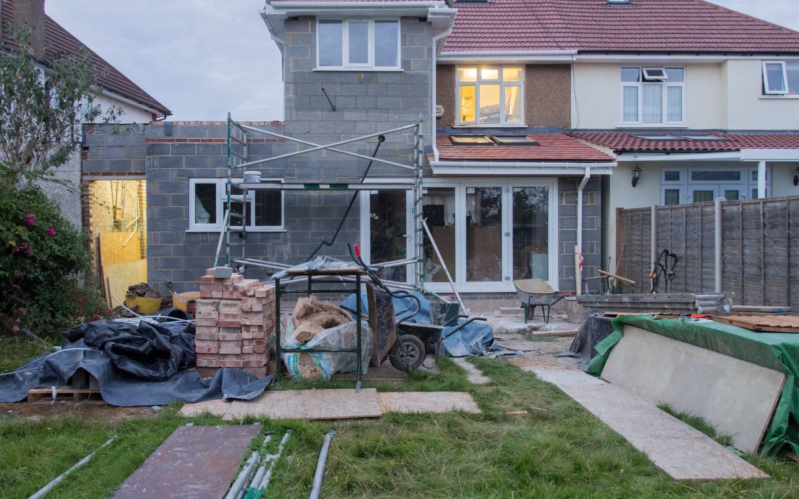 Rear extension under construction on a brick semi-detached house with bricks and rubble bags in the garden